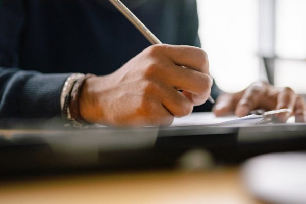 Detailed shot of hands holding a pencil, writing notes on paper.
