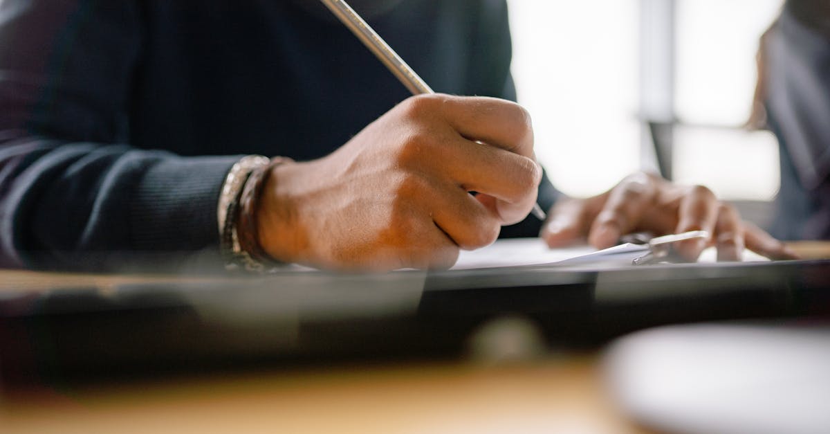 Detailed shot of hands holding a pencil, writing notes on paper.